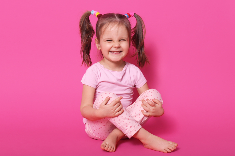 indoor-laughing-positive-kid-sitting-floor-posing-isolated-pink-wearing-rose-t-shirt-trousers-having-ponytails-being-high-spirits-childhood-concept